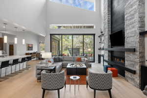 Living room with a high ceiling, light hardwood / wood-style floors, and a fireplace