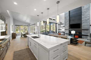 Kitchen featuring decorative light fixtures, sink, a stone fireplace, and plenty of natural light