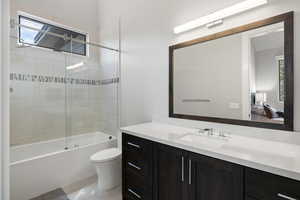 Full bathroom featuring tile flooring, combined bath / shower with glass door, toilet, and vanity