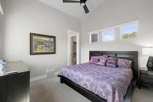 Carpeted bedroom featuring ceiling fan and vaulted ceiling