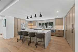 Kitchen featuring tasteful backsplash, a kitchen breakfast bar, a kitchen island, and light wood-type flooring