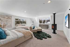 Bedroom featuring light carpet and a wood stove
