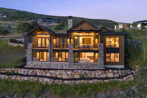 Back house at dusk featuring a balcony and a mountain view