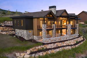 Back house at dusk with a pergola and a balcony