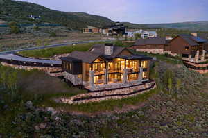 Back house at dusk featuring a mountain view and a balcony