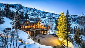 Snow covered rear of property with a mountain view and a balcony