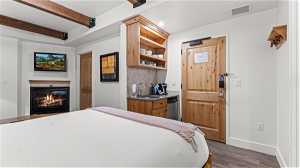 Bedroom featuring sink, dark hardwood flooring, and beamed ceiling