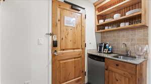 Kitchen featuring sink, dark stone countertops, dishwasher, and tasteful backsplash