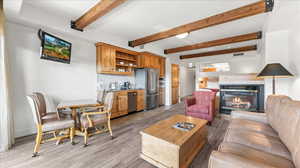 Living room featuring sink, light hardwood floors, a tiled fireplace, and beamed ceiling