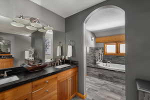 Full bath featuring tiled tub and double vanity
