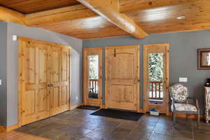 Foyer with wood ceiling, baseboards, and stone tile floors