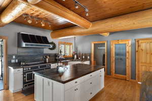 Kitchen with custom exhaust hood, rail lighting, range with two ovens, butcher block countertops, and wood ceiling