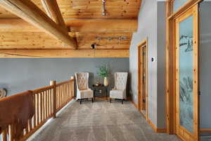 Sitting room with carpet floors, track lighting, wooden ceiling, and baseboards