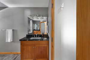 Bathroom with vanity, wood finished floors, and baseboards