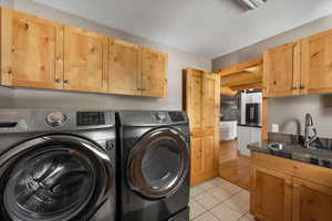 Laundry room with separate washer and dryer, cabinet space, and light tile patterned flooring