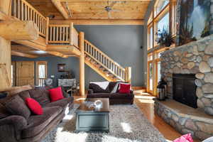Living area with wood finished floors, stairs, a fireplace, wooden ceiling, and ceiling fan