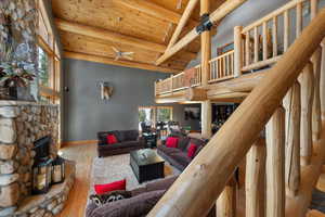Living room with high vaulted ceiling, wooden ceiling, a ceiling fan, beamed ceiling, and wood finished floors
