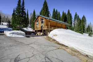 View of front of house featuring log siding, asphalt driveway, and a deck