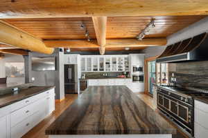Kitchen featuring high end fridge, track lighting, oven, wooden ceiling, and beverage cooler