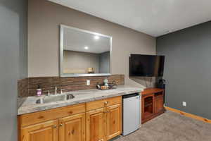 Kitchen with refrigerator, a sink, light carpet, decorative backsplash, and light countertops