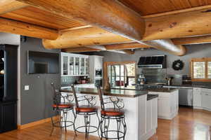 Kitchen featuring extractor fan, stainless steel dishwasher, a center island, wooden ceiling, and tasteful backsplash