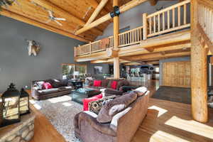 Living room with a ceiling fan, high vaulted ceiling, beamed ceiling, wood ceiling, and wood finished floors