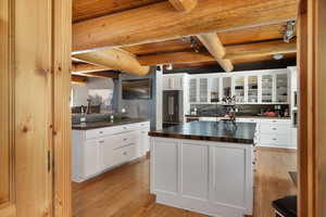 Kitchen featuring high end fridge, dark countertops, wooden ceiling, light wood-type flooring, and beam ceiling