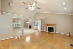 Unfurnished living room featuring a towering ceiling, light parquet floors, crown molding, and ceiling fan
