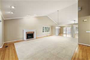 Bright Open Living Room featuring high vaulted ceilings, light carpet and hardwood flooring
