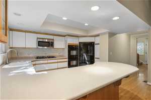 Kitchen featuring tasteful backsplash, solid surface countertops, white cabinets, and stainless appliances