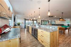 Kitchen with a center island with sink, wine cooler, hanging light fixtures, billiards, and light brown cabinets