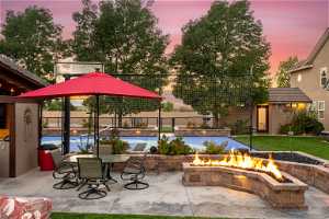 Patio terrace at dusk with an outdoor fire pit and a pool