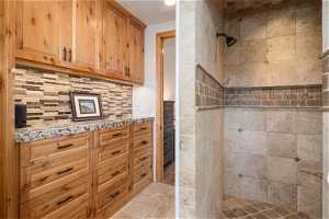 Bathroom with backsplash, wood-type flooring, and tiled shower