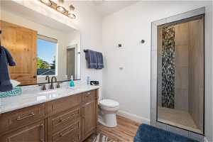 Bathroom featuring toilet, hardwood flooring, a tile shower, and vanity