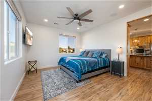 Bedroom featuring multiple windows, ceiling fan, stainless steel fridge, and light hardwood flooring