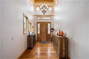 Wood floored foyer entrance featuring a towering ceiling and an inviting chandelier