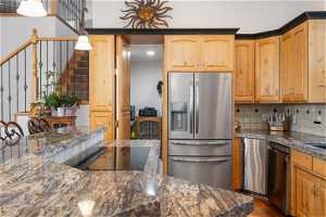 Kitchen featuring pendant lighting, dark hardwood flooring, appliances with stainless steel finishes, backsplash, and dark stone counters