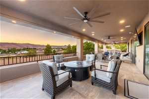 Patio terrace at dusk with a balcony, a mountain view, ceiling fan, and an outdoor hangout area