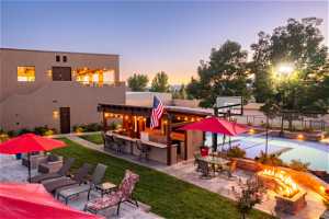 Pool at dusk with a patio, an outdoor bar, and a fire pit
