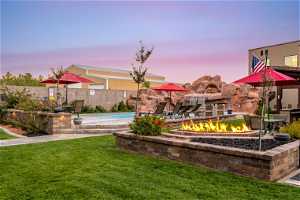 Yard at dusk with a fenced in pool and a fire pit
