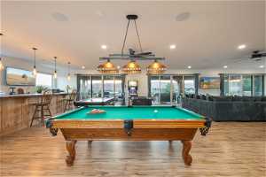 Recreation room with bar, pool table, light hardwood floors, and ceiling fan