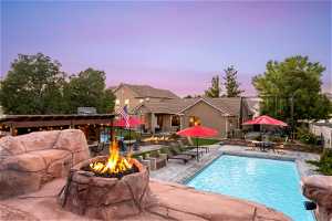 Pool at dusk featuring a patio area and an outdoor fire pit