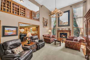 Living room with an inviting chandelier, carpet flooring, and a high ceiling