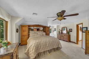 Bedroom featuring light carpet, multiple windows, ceiling fan, and a textured ceiling