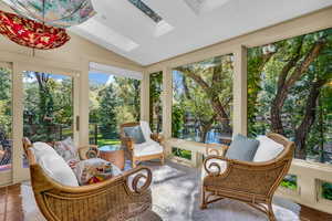 Sunroom / solarium featuring a water view and vaulted ceiling with skylight