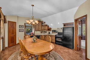 Dining space with vaulted ceiling, sink, and a notable chandelier