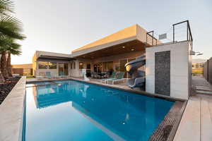 Pool at dusk with a water slide and a patio