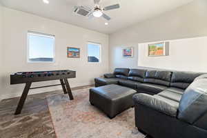 Living room with vaulted ceiling, ceiling fan, and light hardwood / wood-style flooring