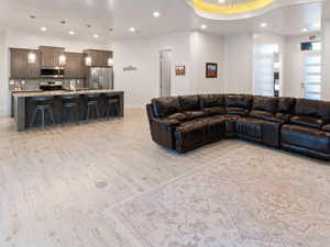 Living room featuring a tray ceiling, light hardwood / wood-style flooring, and ceiling fan