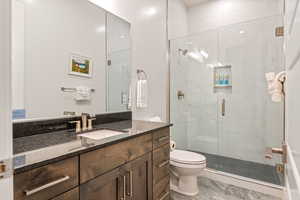 Bathroom featuring tile floors, a shower with door, large vanity, and toilet